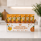 Open Peanut Power Smoothie Box with six orange smoothie pouches on a kitchen counter