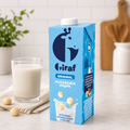 Giraf Original macadamia drink carton beside a filled glass and macadamia nuts on a kitchen counter