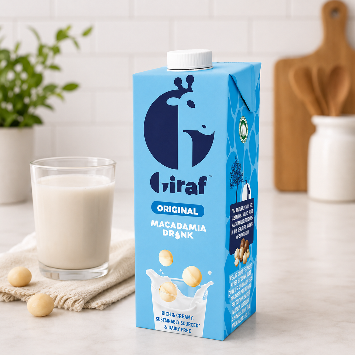 Giraf Original macadamia drink carton beside a filled glass and macadamia nuts on a kitchen counter
