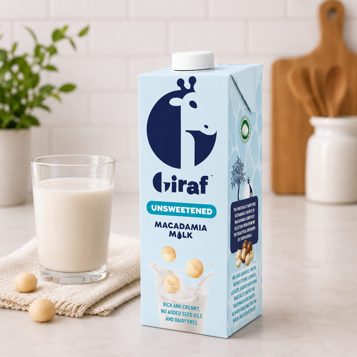 Giraf unsweetened macadamia milk carton beside a filled glass and macadamia nuts on a kitchen counter