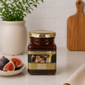 Jar of Froggit red fig chutney with gold lid, displayed beside fresh figs on a kitchen counter