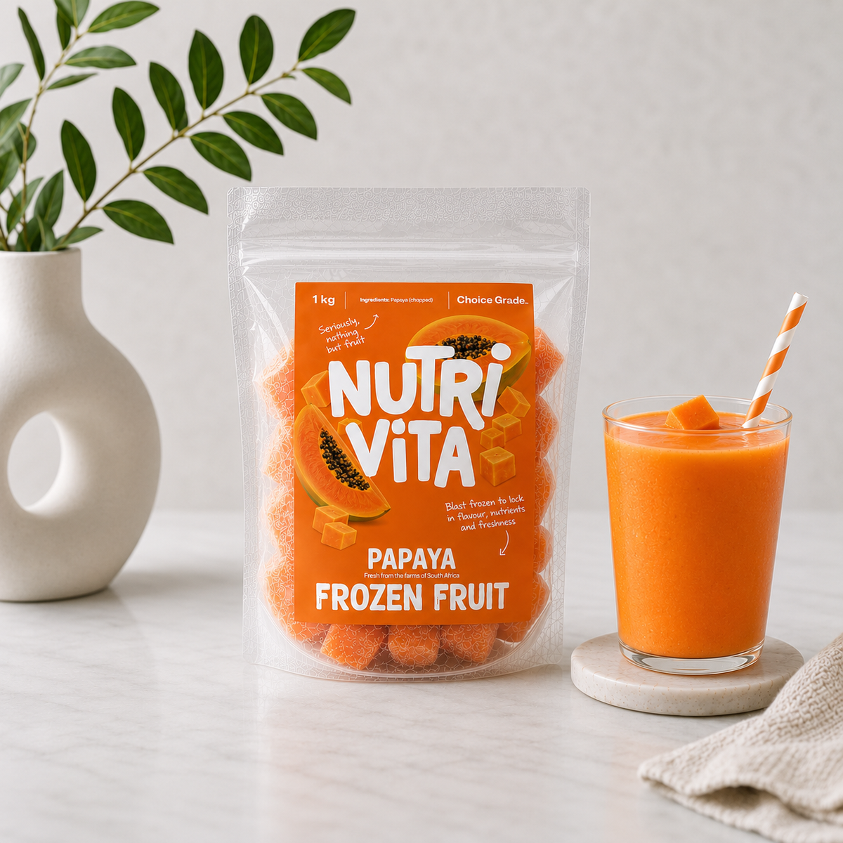 Nutri Vita papaya frozen fruit pouch beside a glass of orange papaya smoothie