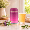 Pink CultureLab Kombucha Konfettibos can beside a glass of sparkling amber kombucha